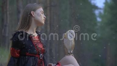 一个穿着黑色连衣裙的长发女孩审视着一只猫头鹰坐在膝盖上，羽毛从天空中<strong>飘落</strong>，动作缓慢